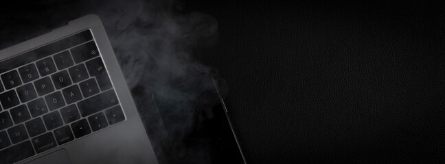 smoke over laptop and phone on black background