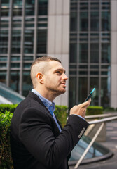 Photo of a young and attractive business man wearing smart casual clothes sending and audio with is phone in a job break