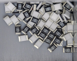 Grey scattered microscopic SMT surface mount chip resistors sorted in grey storage container