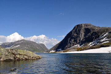 Cold mountain lake in Norway with snow and ice and mountains nearby.