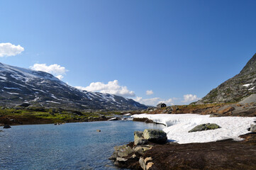 Fototapeta na wymiar Cold mountain lake in Norway with snow and ice and mountains nearby.