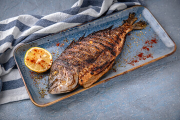 Grilled dorado. Natural delicious food. Greek cuisine menu. Still life in a marine style on a blue background.
