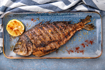 Grilled dorado. Natural delicious food. Greek cuisine menu. Still life in a marine style on a blue background.