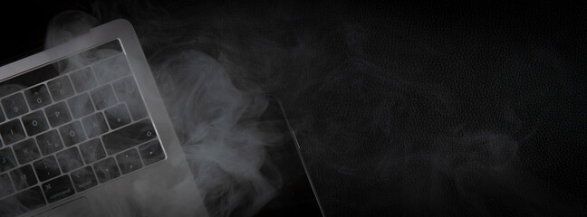 smoke over laptop and phone on black background