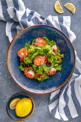A light, nutritious salad of shrimp, lettuce and olives. Natural delicious food. Greek cuisine menu. Still life in a marine style on a blue background.