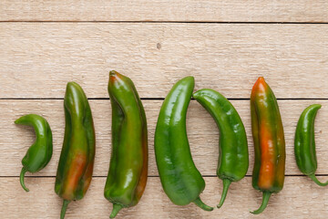 Group of green peppers on old wooden table. Top view.