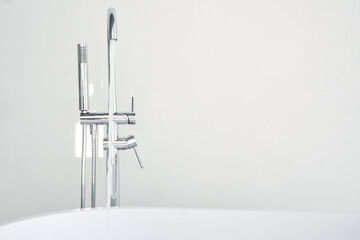 Faucet fills a bathtub in a white bathroom close-up, nobody
