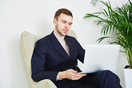 Successful businessman in a suit in a chair with a computer works comfortably at home