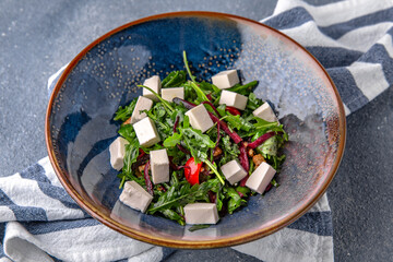 Arugula salad, cherry tomatoes, beets, olives and feta cheese. Natural delicious food. Greek cuisine menu. Still life in a marine style on a blue background.