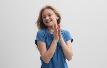 Cheerful young caucasian woman clapping hands isolated on a gray background with smile on face