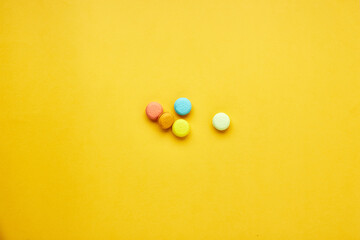 Multicolored macaroon cakes on a yellow background.