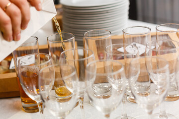White wine being poured into wine glass in restaurant. Set of glasses with juice