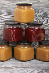 Apple and cranberry preserves in jars. On brushed boards, painted black and white.