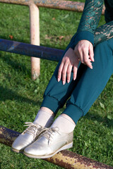 Girl in a green tracksuit and golden shoes. On a Sportsground. Close-up of the legs.