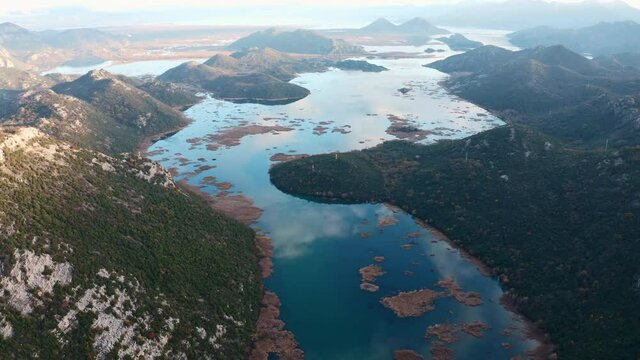 Clouds in blue sky reflected in a lake. Aerial view of the hills surrounding Crnojevica river and Lake Skadar in Montenegro. Beautiful landscape.