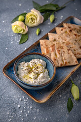 Cottage cheese appetizer sauce with garlic and olive oil with pita. Natural delicious food. Greek cuisine menu. Still life in a marine style on a blue background.
