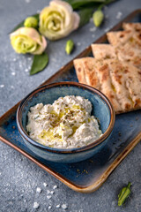Cottage cheese appetizer sauce with garlic and olive oil with pita. Natural delicious food. Greek cuisine menu. Still life in a marine style on a blue background.