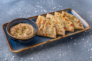 Eggplant appetizer sauce with pita. Natural delicious food. Greek cuisine menu. Still life in a marine style on a blue background.