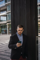 Fototapeta premium Photo of a young and attractive business man checking his phone. Wearing smart casual clothes. Entrepeneur style
