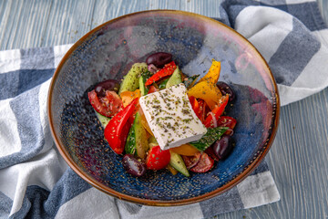 Classic Greek salad. Natural delicious food. Greek cuisine menu. Still life in a marine style on a blue background.
