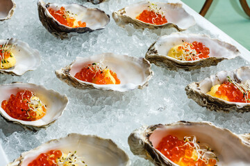 Fresh Oysters close-up on blue plate, served table with oysters, lemon and ice. Healthy sea food. Oyster dinner with champagne in restaurant. Gourmet food.