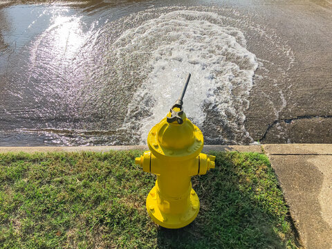 Top View Yellow Fire Hydrant Gushing Water Across A Residential Street Near Dallas, Texas, USA