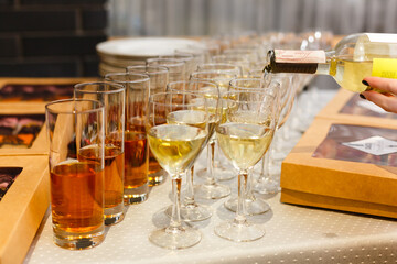 White wine being poured into wine glass in restaurant. Set of glasses with juice