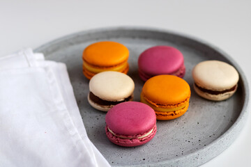 Selective focus to multicolored macarons with cream on a gray plate.