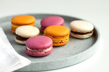 Obraz na płótnie Canvas Selective focus to multicolored macarons with cream on a gray plate.