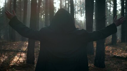 Monk Raising Hands in Prayer. Wanderer Pilgrim in Black Cloak with Cowl Praying in Misty Wood. Autumn Morning. 2x Slow motion 60 FPS