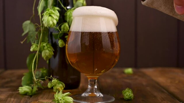 Beer. Cold Craft light Beer in a glass with water drops. Pint of Beer close up on a wooden background. Beer is pouring from the bottle. Border design. High quality 4k footage