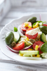 Simple Salad with Green Olives, Cucumber, Cherry Tomatoes and Capers. Bright wooden background. Close up. 