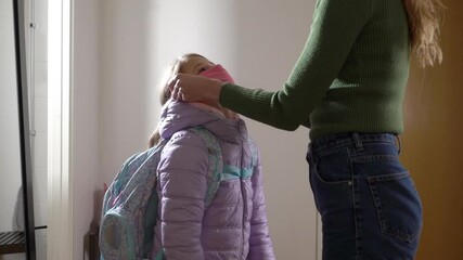 Mom wearing safety face mask to daughter for going to school. Covid-19 protection and social distance during pandemic coronavirus - Powered by Adobe