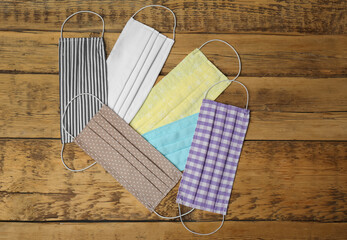 Homemade protective face masks on wooden table, flat lay