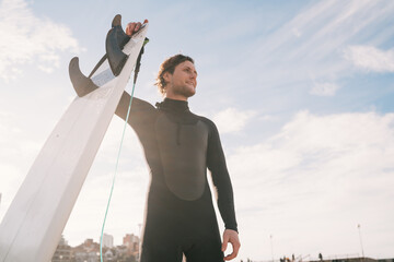 Surfer standing at the beach with surfboard.