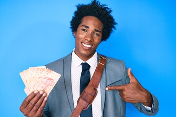 Handsome african american man with afro hair holding mexican pesos pointing finger to one self smiling happy and proud