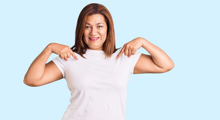 Middle age latin woman wearing casual white tshirt looking confident with smile on face, pointing oneself with fingers proud and happy.