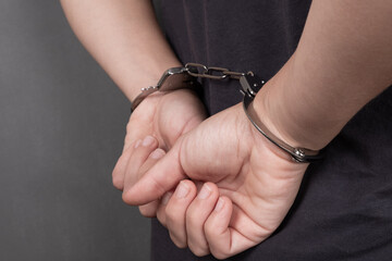 arrested person in handcuffs on a dark background close-up, chained hands on the back