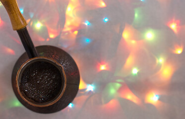 cezve with coffee on a background of colored lights