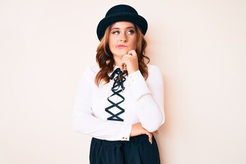 Young beautiful caucasian woman wearing elegant style and hat thinking concentrated about doubt with finger on chin and looking up wondering