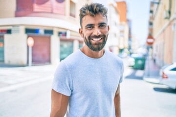 Young hispanic man smiling happy walking at the city