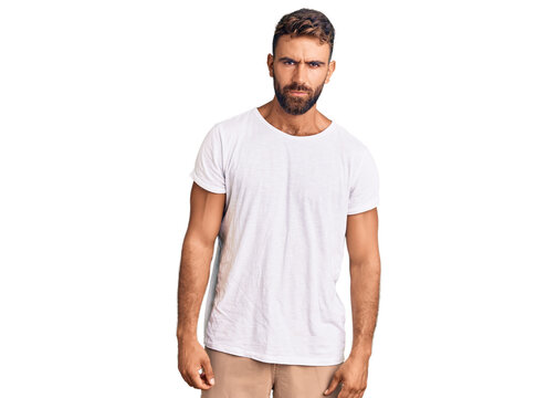 Young hispanic man wearing casual white tshirt skeptic and nervous, frowning upset because of problem. negative person.