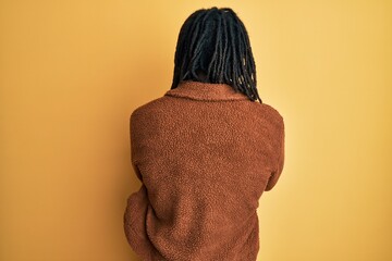 African american man with braids wearing brown retro jacket standing backwards looking away with...