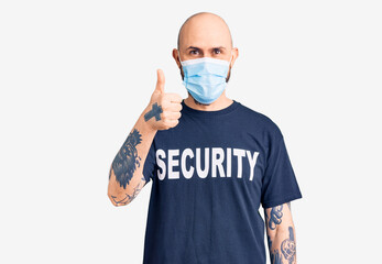 Young handsome man wearing security t shirt and medical mask smiling happy and positive, thumb up doing excellent and approval sign