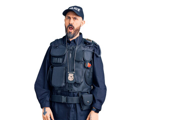 Young handsome man wearing police uniform in shock face, looking skeptical and sarcastic, surprised...