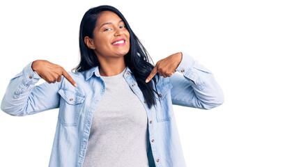 Hispanic woman with long hair wearing casual denim jacket looking confident with smile on face,...
