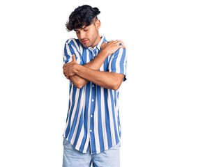 Young hispanic man wearing casual clothes hugging oneself happy and positive, smiling confident....