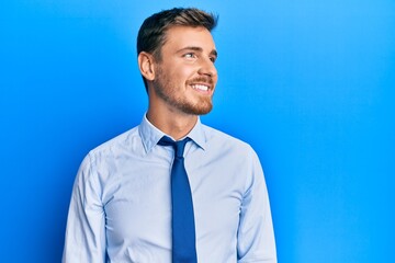 Handsome caucasian man wearing business shirt and tie looking away to side with smile on face, natural expression. laughing confident.