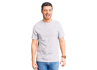 Fototapeta premium Handsome young man with bear wearing casual tshirt winking looking at the camera with sexy expression, cheerful and happy face.