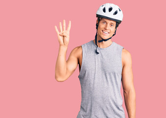 Young handsome man wearing bike helmet showing and pointing up with fingers number four while smiling confident and happy.